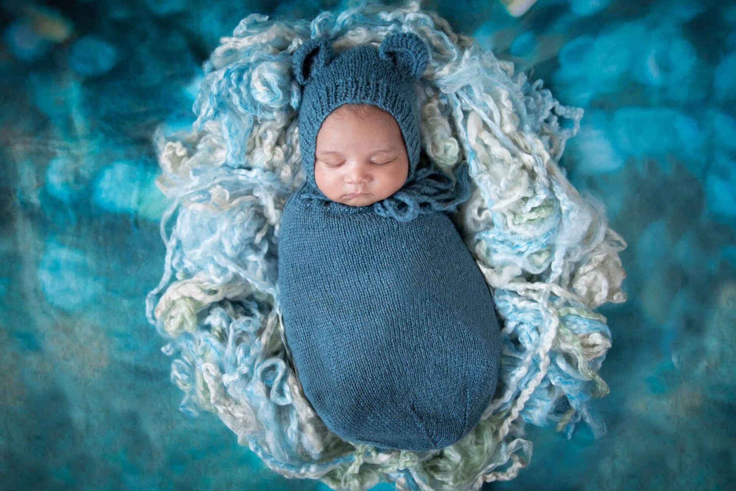 Bird view one month new baby boy in slate blue mohair bonnet and snuggle sack - www.musenphotos.com - in-home newborn session - central New Jersey