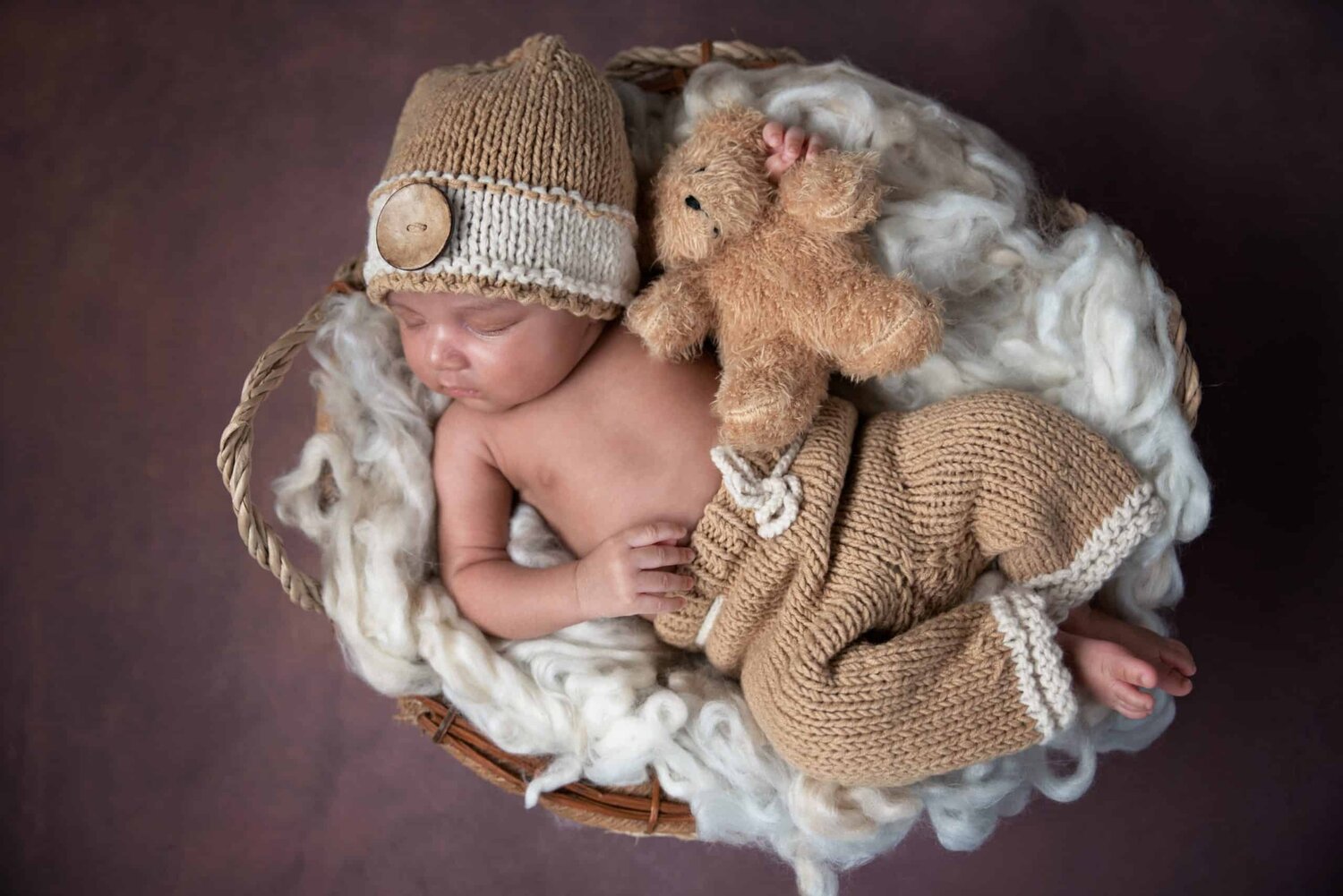 One month new baby boy in brown outfits holding bear bird view basket shoot - www.musenphotos.com - in-home newborn session - central New Jersey