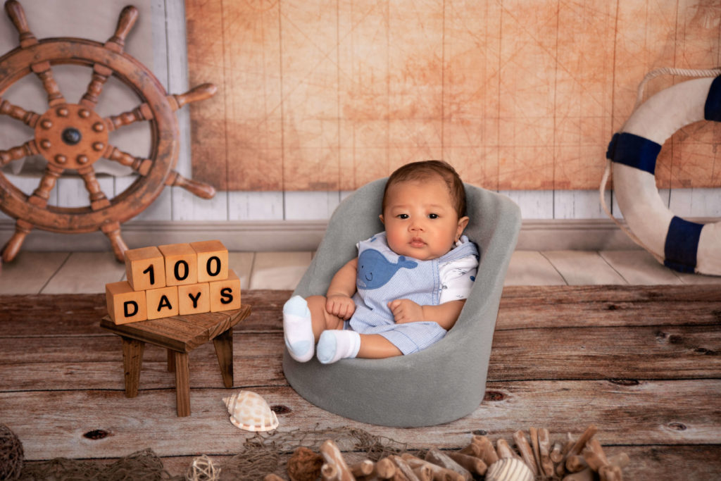 Nautical theme with 100 days wood sign baby in gray posing chair